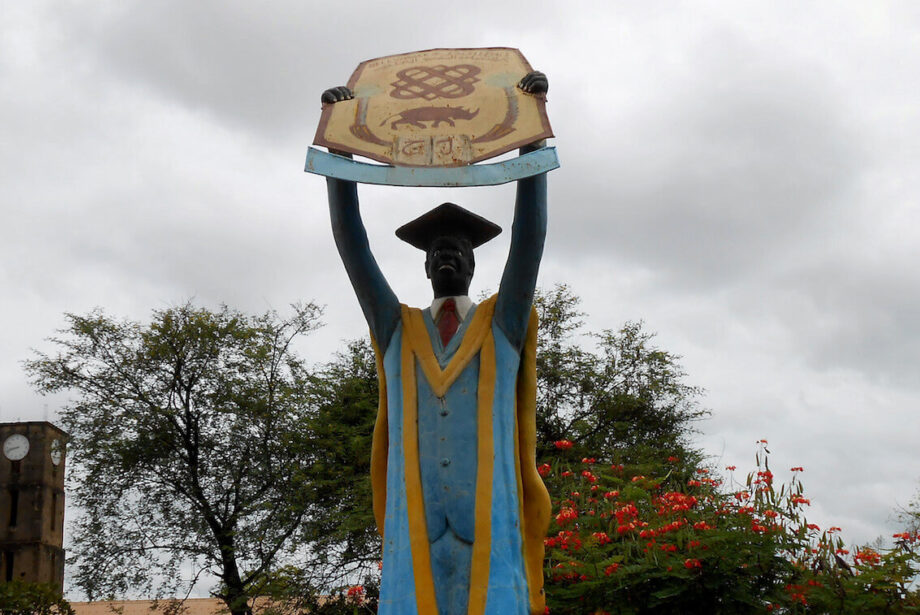 Large statue of graduate holding up sign.