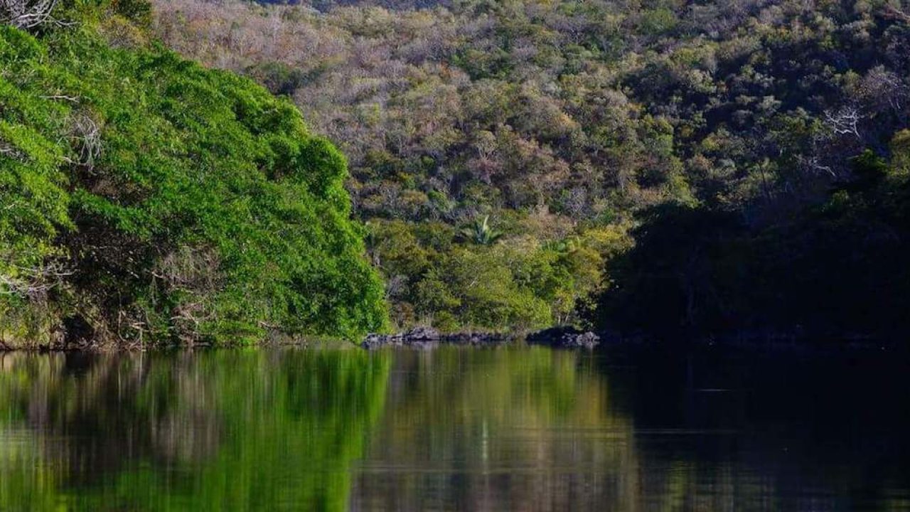 Dark river surrounded by green and brown hills.