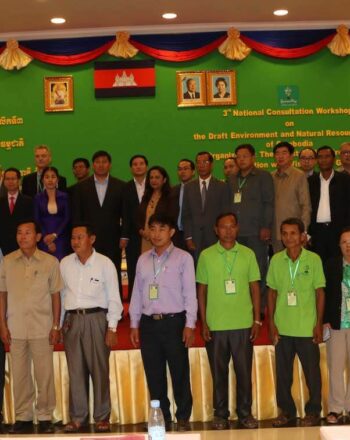 Group of about 30 people standing on and in front of a small stage.