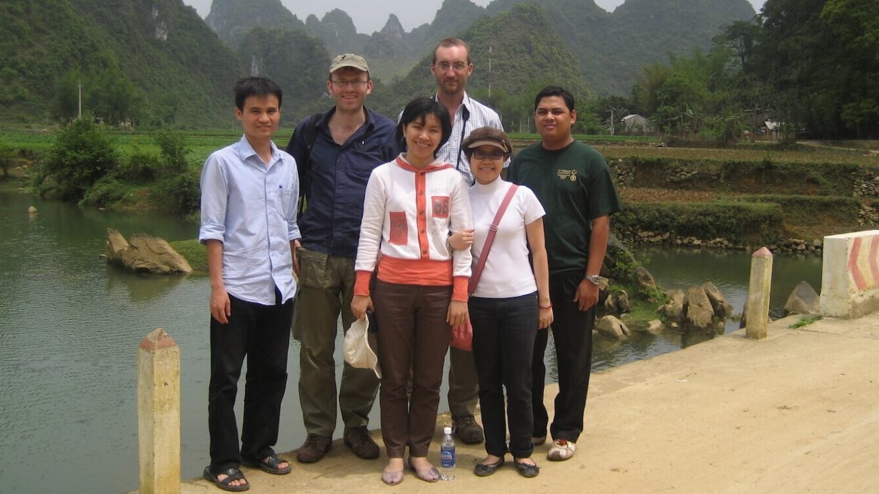 Group of people standing, smiling at camera.
