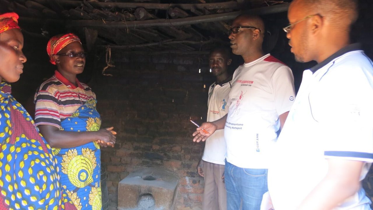 2 women, 3 women, standing, stove behind them.