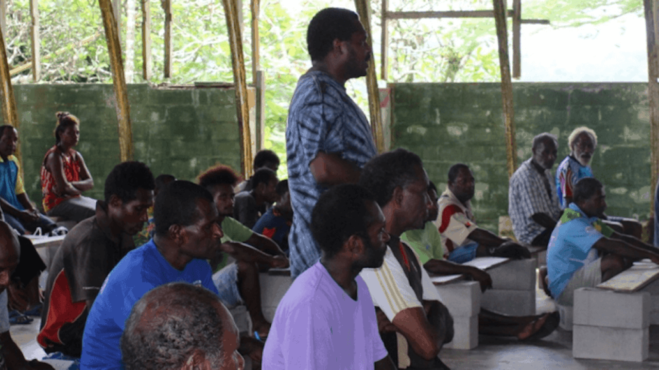 Man standing at open-air meeting.