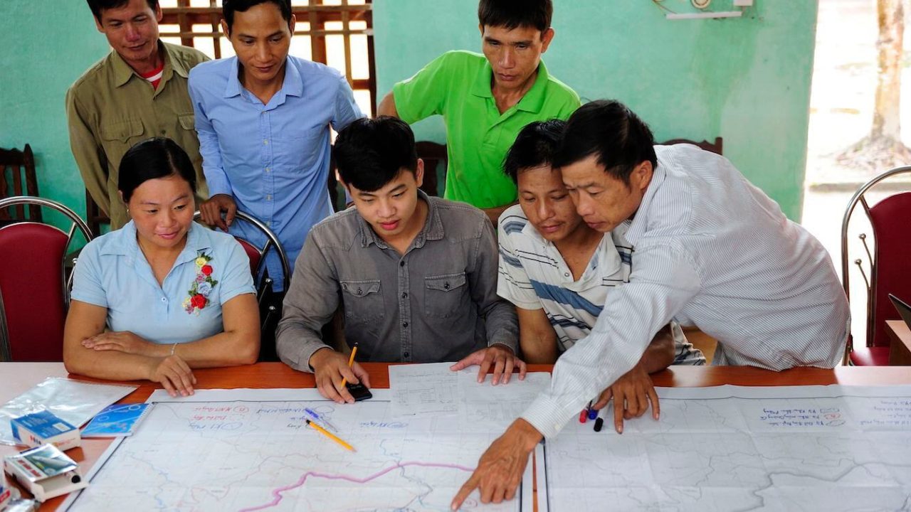Small group of people looking at and pointing to a map.