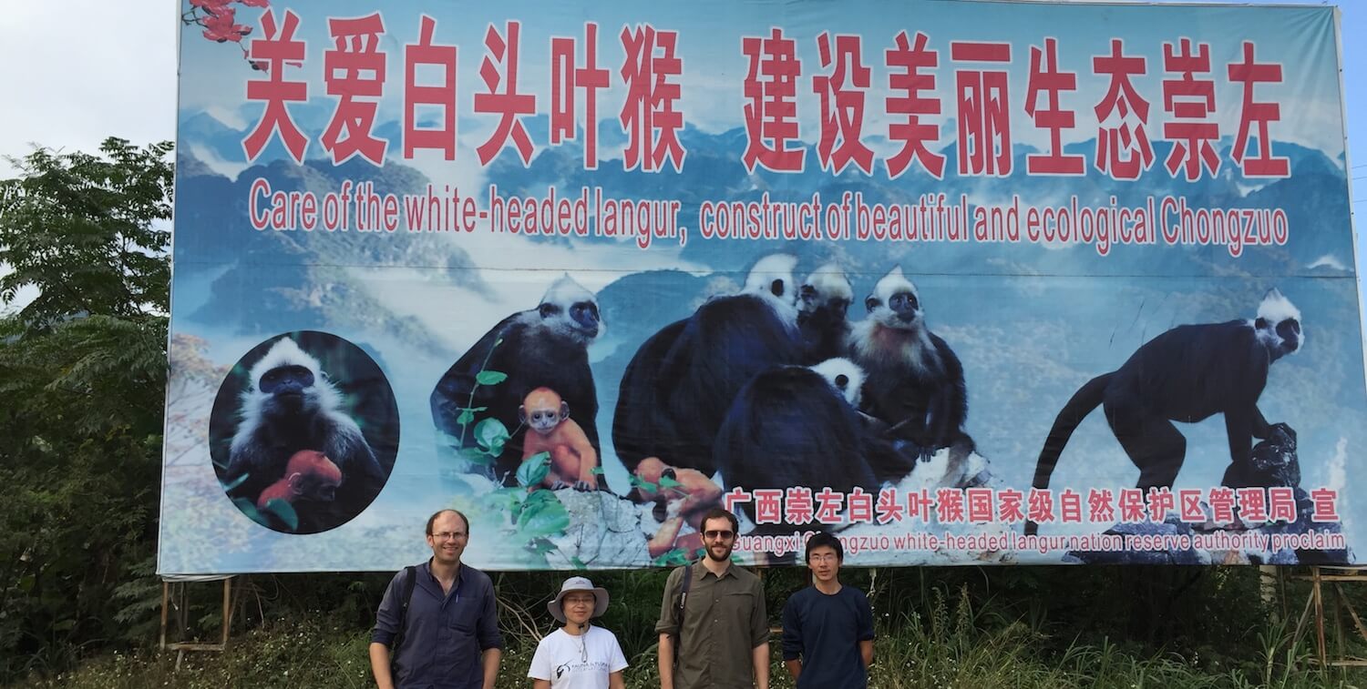 Large sign, four people standing underneath.