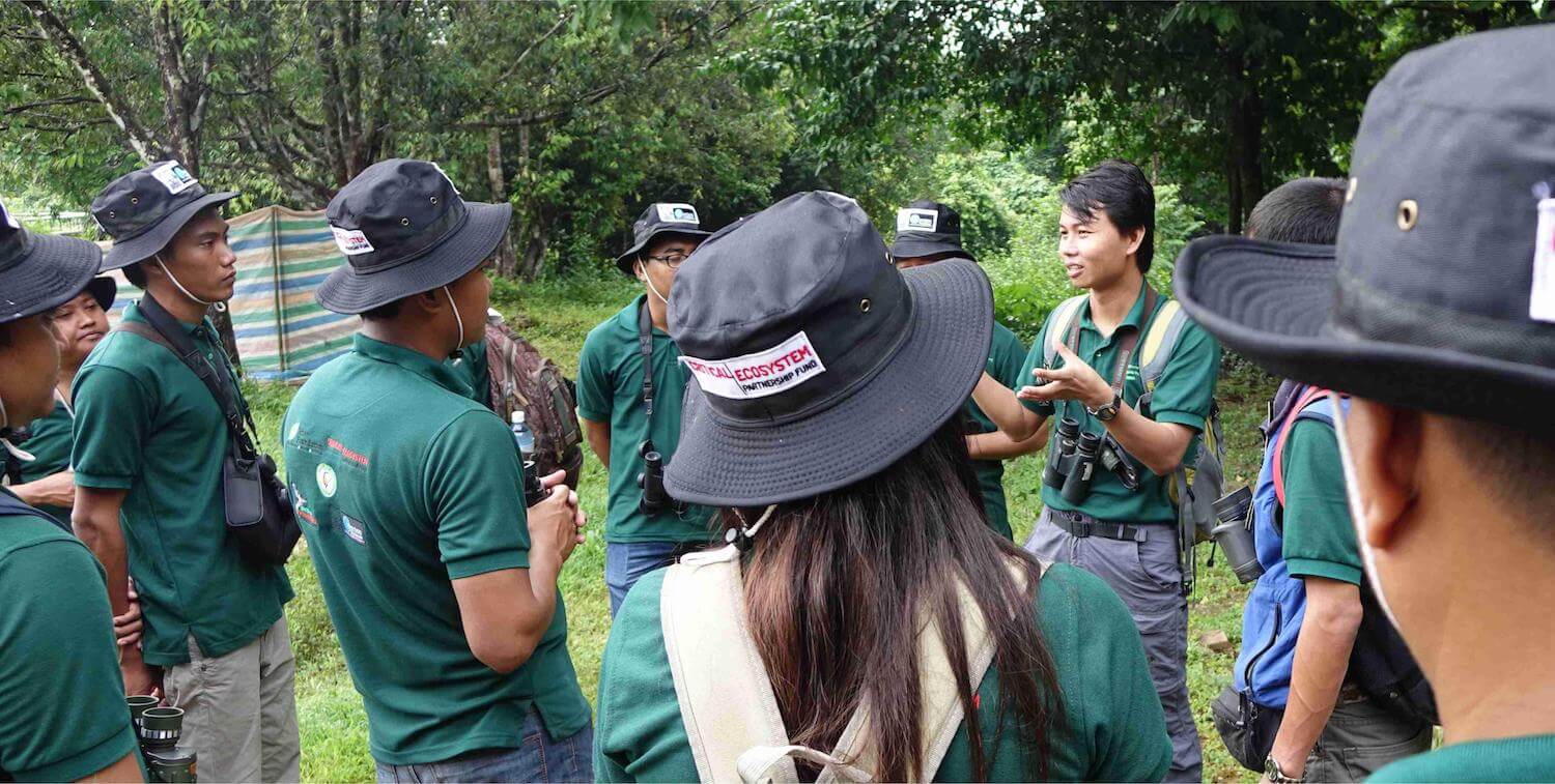 Small group wearing CEPF bucket hats standing outside around man giving instructions.