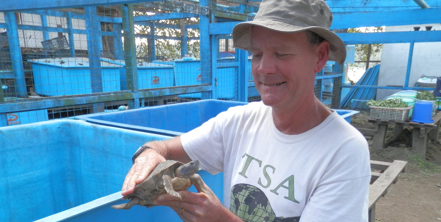 Hombre con camisa TSA sosteniendo una pequeña tortuga.