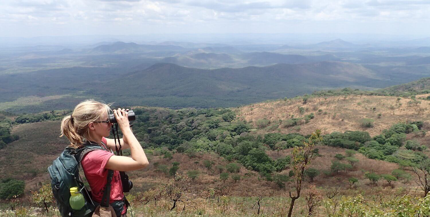 Woman looking through binoculars out at vista