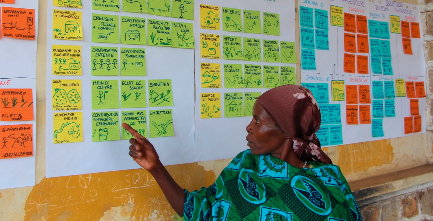 Woman pointing to colorful notes on a wall.