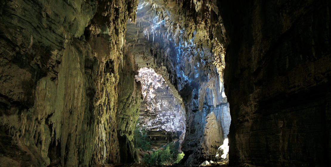 Inside a large cave with light filtering in.