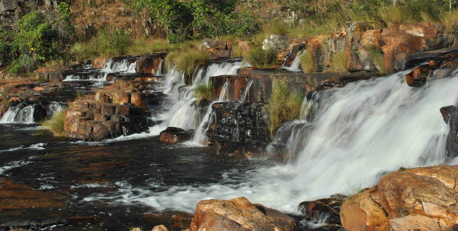 Group of small waterfalls over brown rocks.