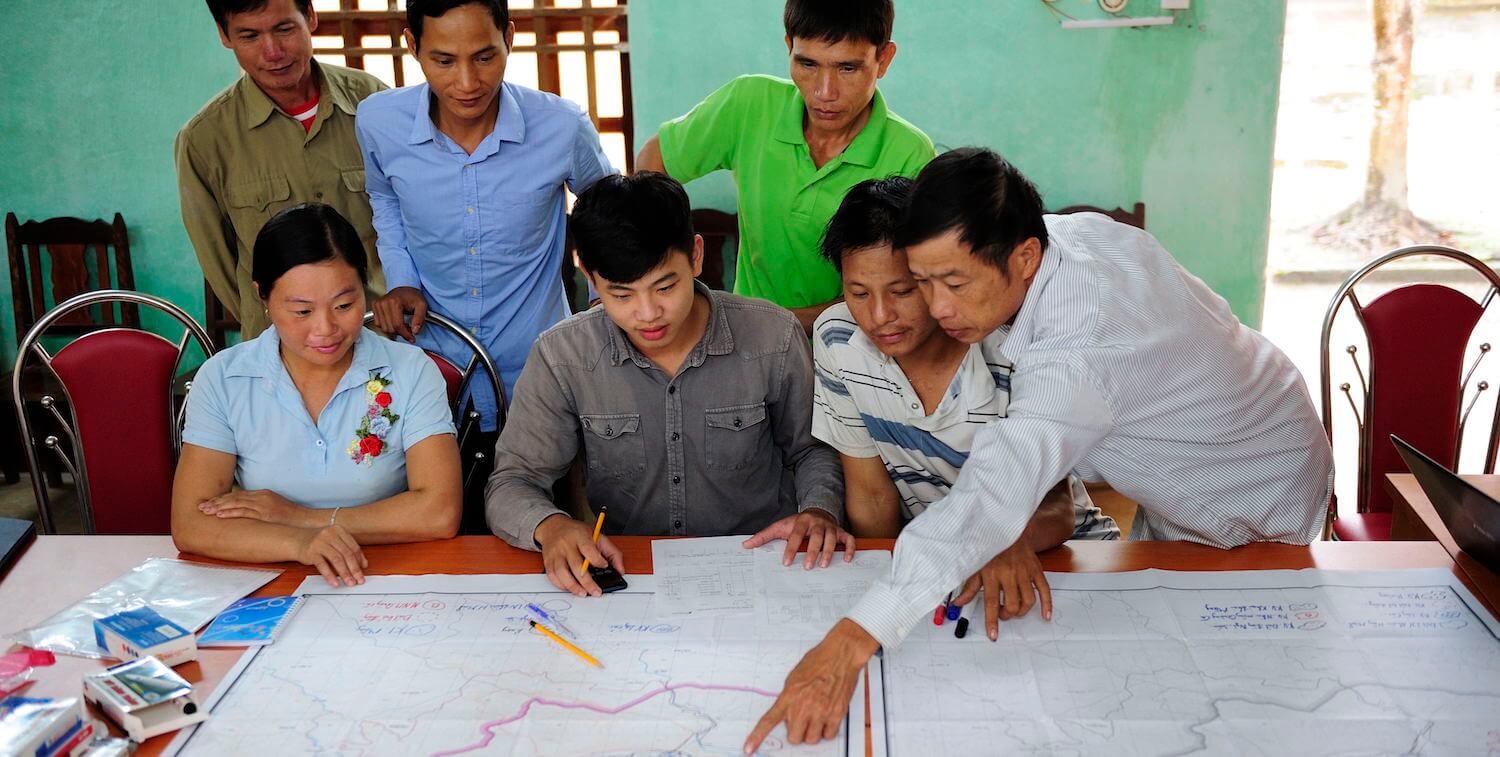 Pequeño grupo de personas mirando y señalando un mapa.