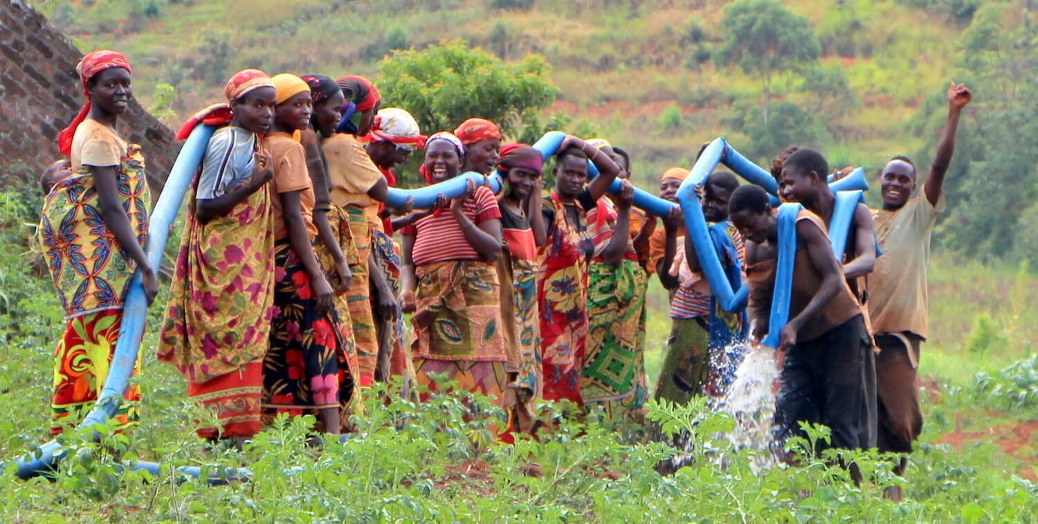 灌漑パイプラインを保持している笑顔の人々のグループ。