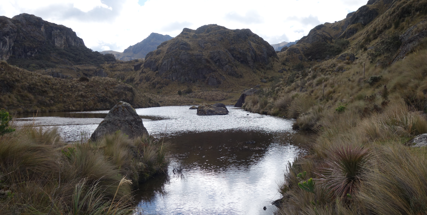 Agua en un valle que refleja el cielo y las colinas rocosas.