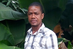 Head shot of Emmanuel Smith standing in front of tree with large branches.
