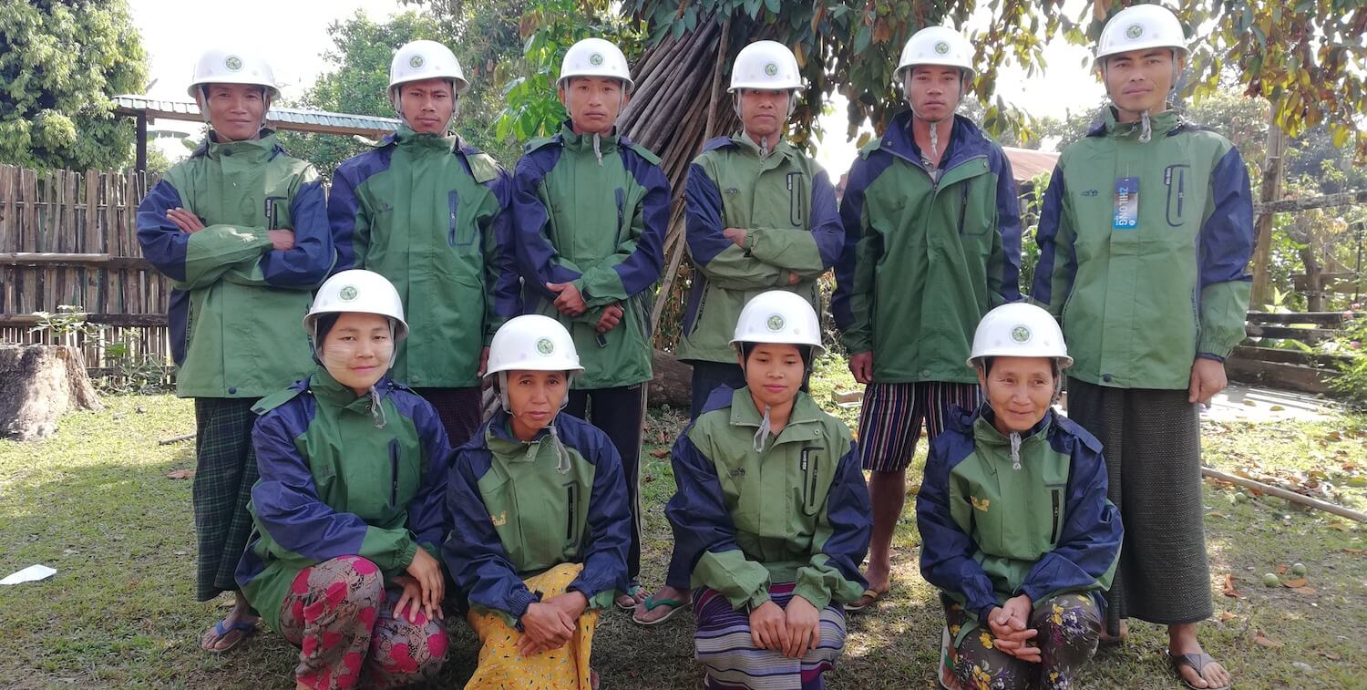 Grupo de 10 hombres y mujeres, con cascos blancos y chaquetas verdes a juego.