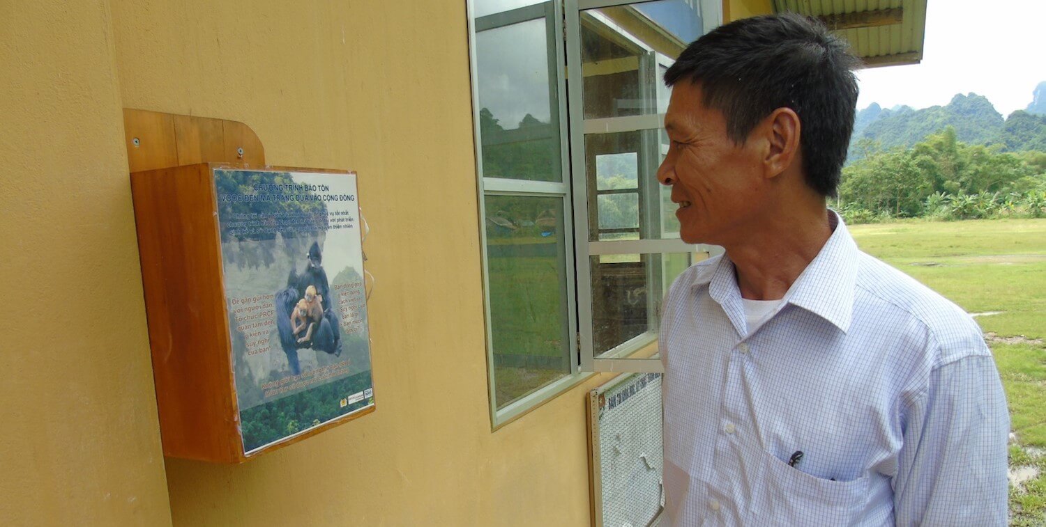 Man looking at box on wall with writing and photo of François' langur.