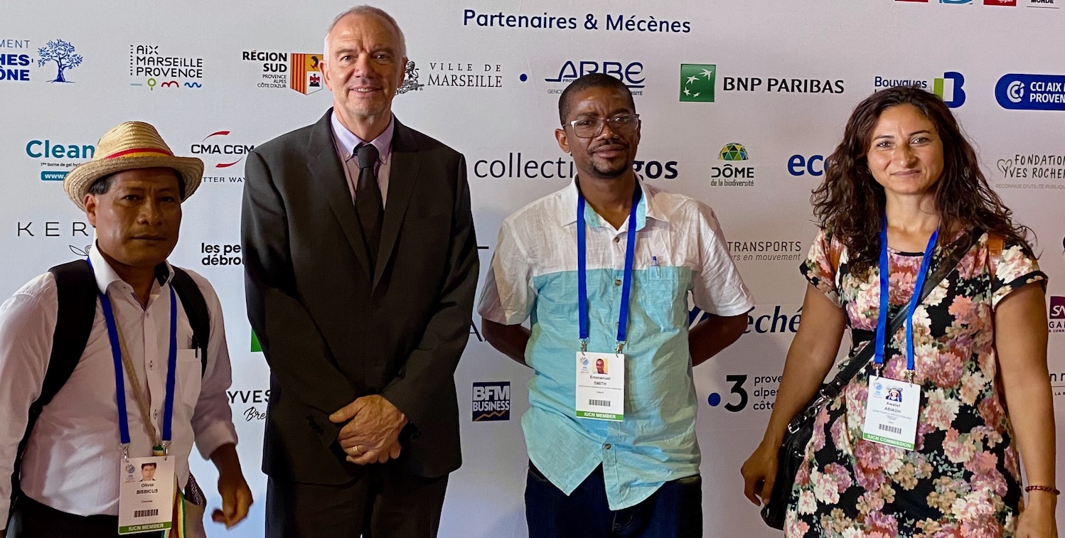 Three men and a woman stand smiling.