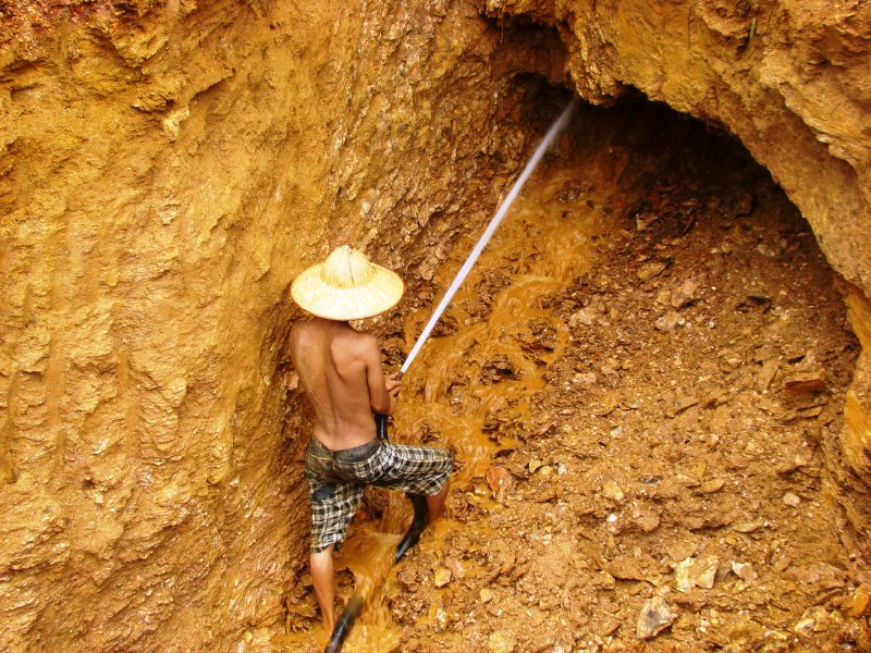 Hombre rociando agua de una manguera en una cueva dorada.