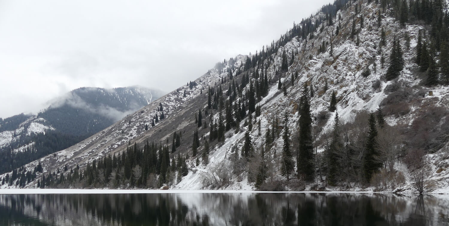 Montaña nevada, lago tranquilo en primer plano.