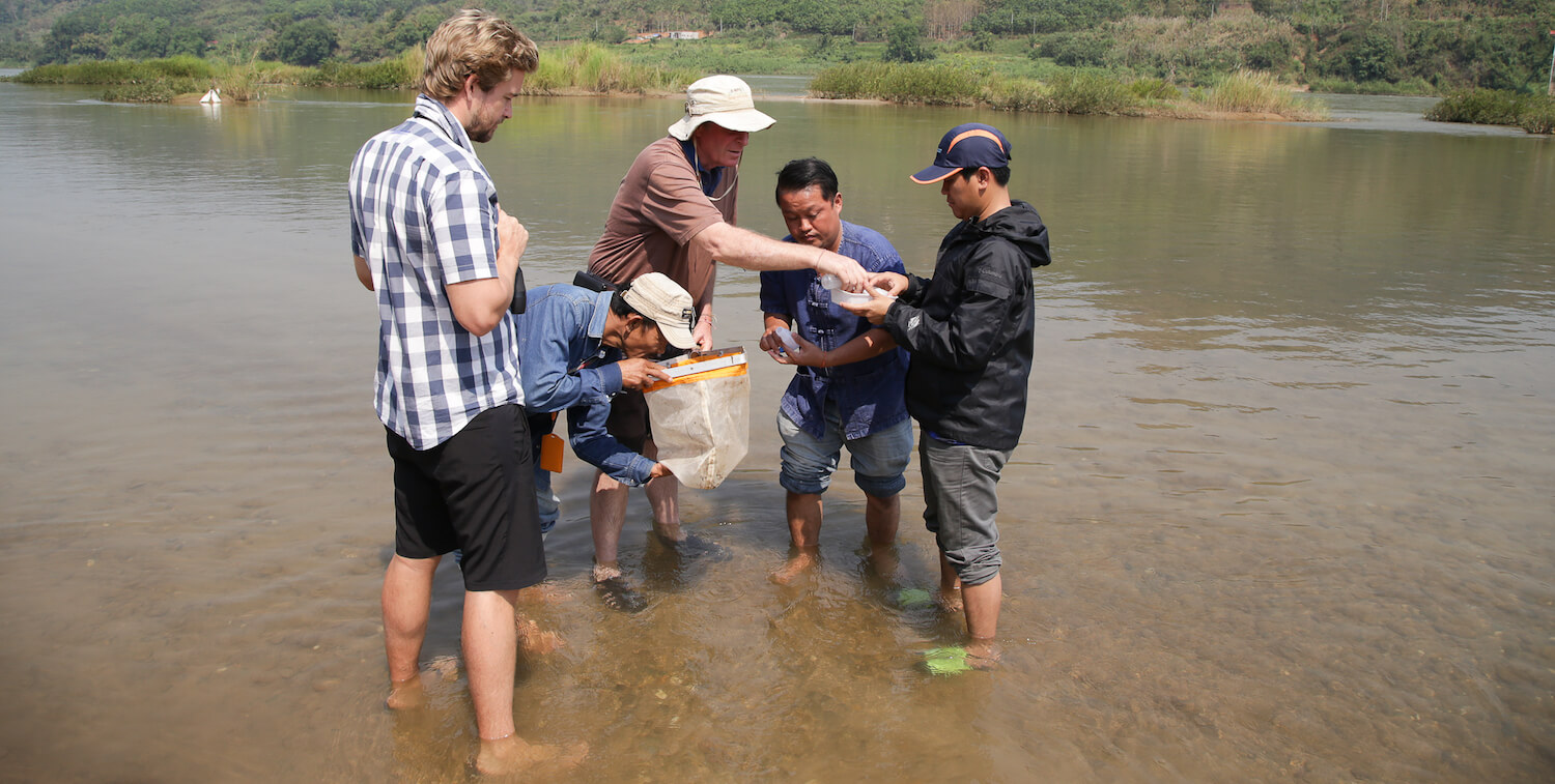 Cinco hombres en el agua hasta los tobillos, trabajando juntos.