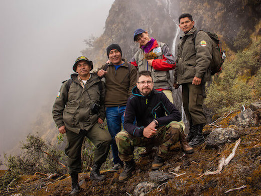 山の上に立って、カメラに微笑んでいる5人のグループ。