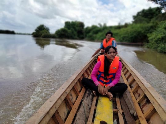 Una mujer mira desde la parte delantera de un pequeño bote mientras monitorea un lago en Camboya.