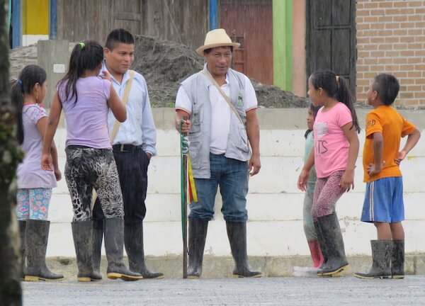 Olivio avec un jeune homme et cinq enfants, debout sous la pluie.