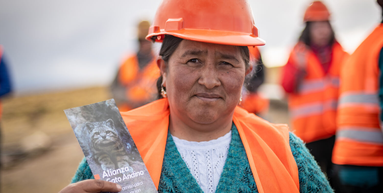 Mujer con casco naranja y chaleco sosteniendo panfleto informativo
