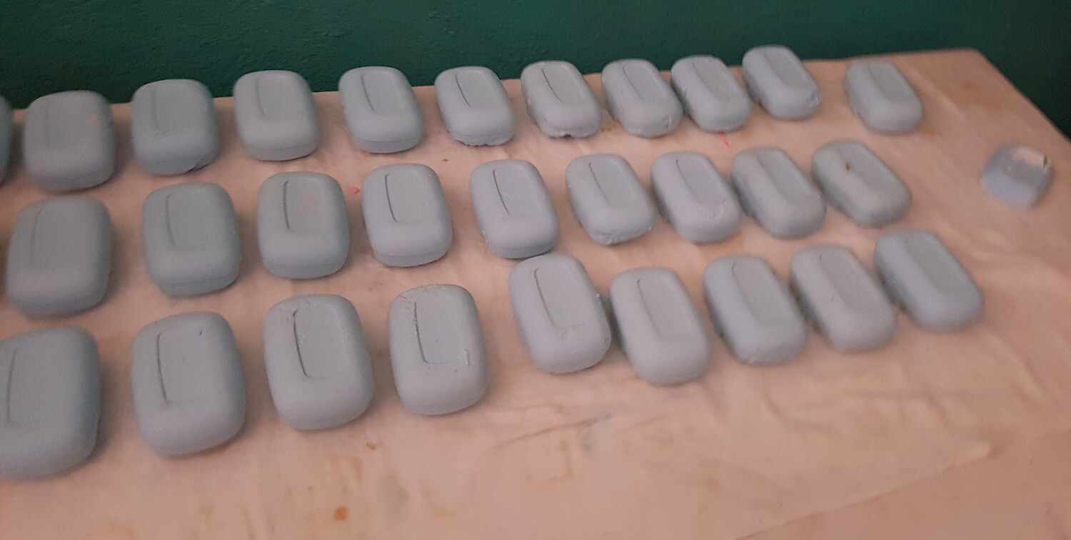 27 bars of gray soap laid out on a table.