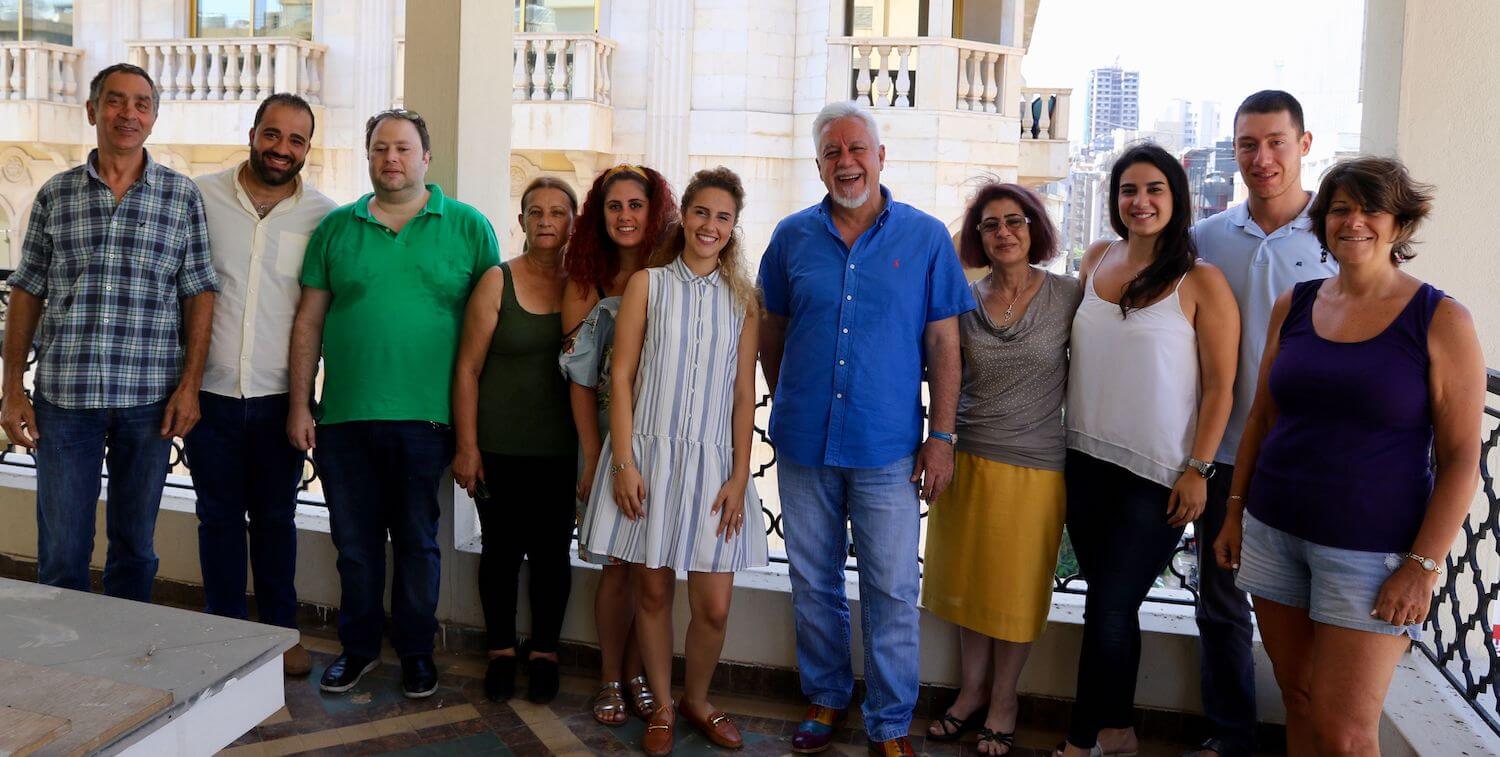 Grupo de 11 mujeres y hombres de pie, sonriendo a la cámara.