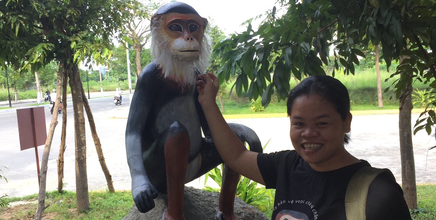 Mujer sonriente junto a una estatua de 4 pies de altura.