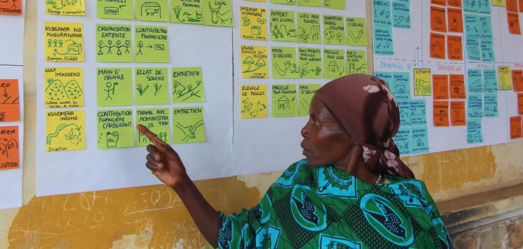 Une femme pointe du doigt l'une des nombreuses notes sur un tableau d'affichage illustrant les éléments d'un plan d'action.