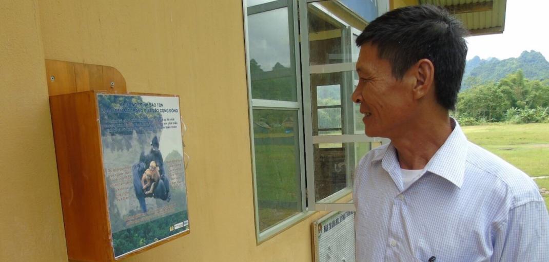 Man looking at box on wall with writing and photo of François' langur.