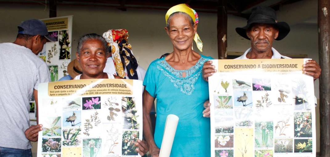Deux femmes et un homme, tous membres d'une communauté Kalunga au Brésil, brandissent des affiches d'éducation environnementale.