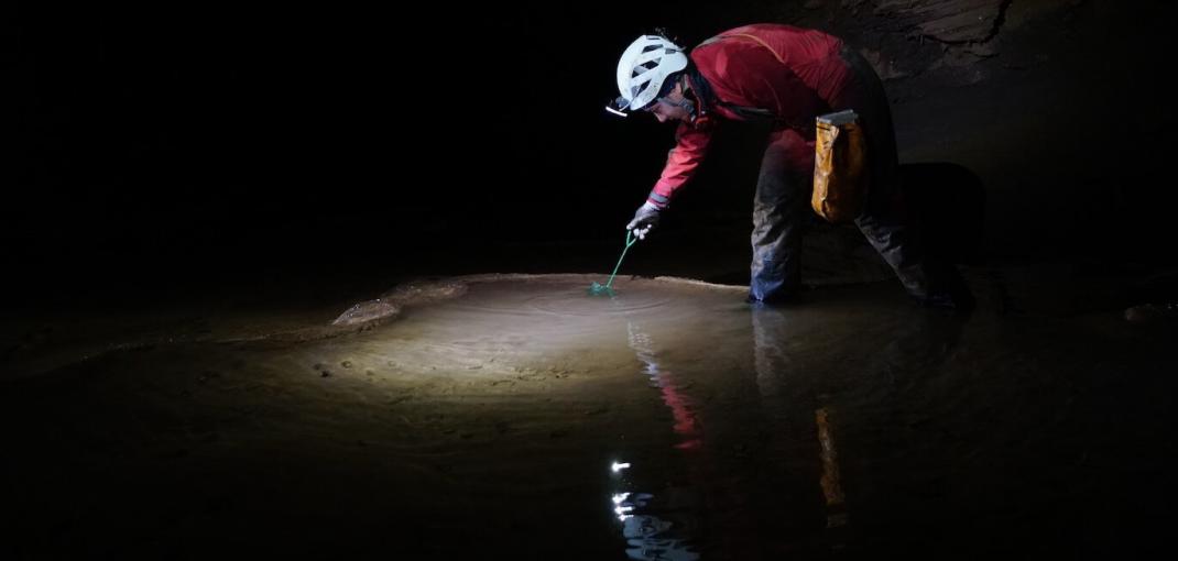 Personne dans la grotte prenant un échantillon d'eau.