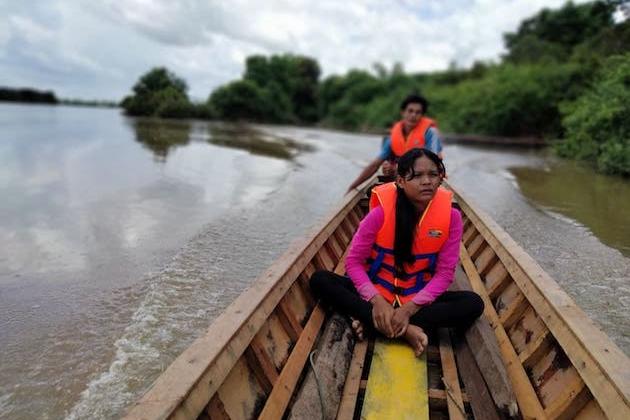 Una mujer mira desde la parte delantera de un pequeño bote mientras monitorea un lago en Camboya.