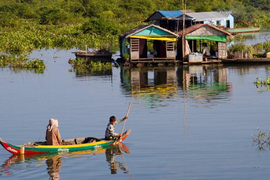 Canoa de colores brillantes en el lago con dos personas, se dirigió hacia varios edificios flotantes.