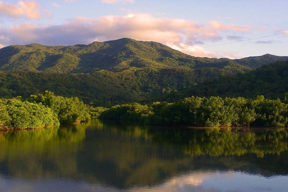 Dark water in the foreground, lush hills in the background.