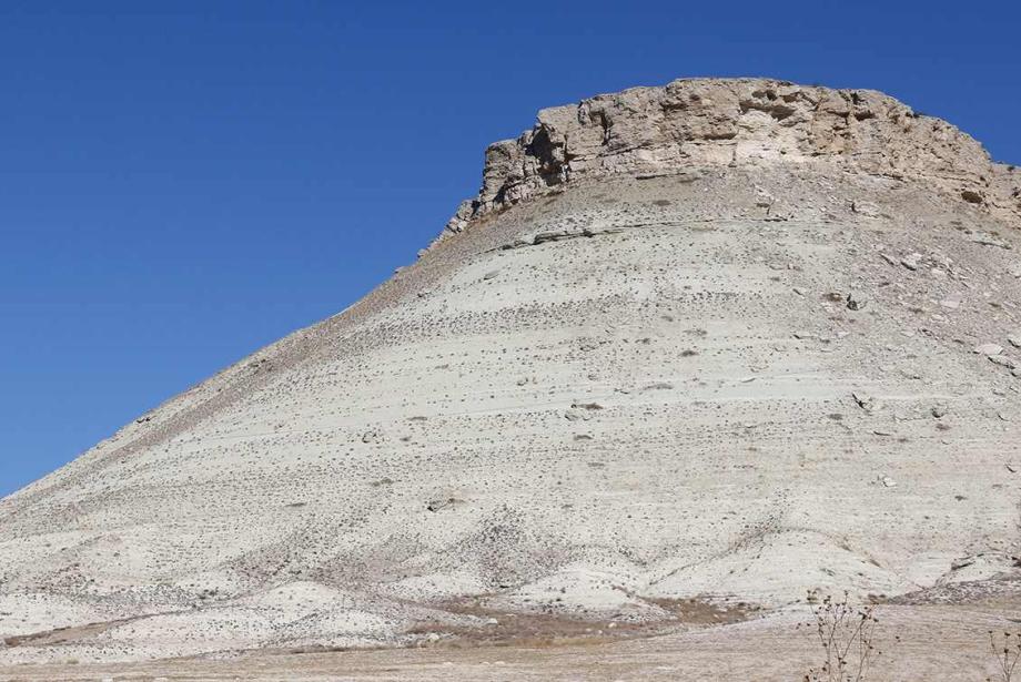 Small, rocky mountain against blue sky.