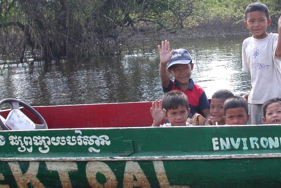 Niños saludando desde un bote pequeño.