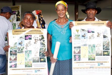 Three people, two women and one man, face camera. Two hold posters.
