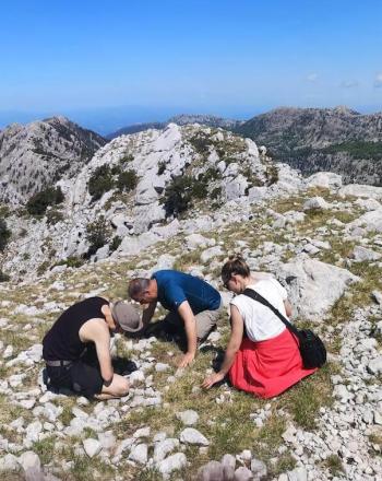 Tres personas en la cima de una montaña rocosa.