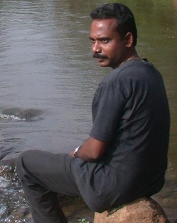 Man looking over shoulder, sitting by moving water.