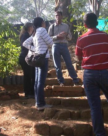 Cinco personas se paran en medio de muchas plantas en macetas.