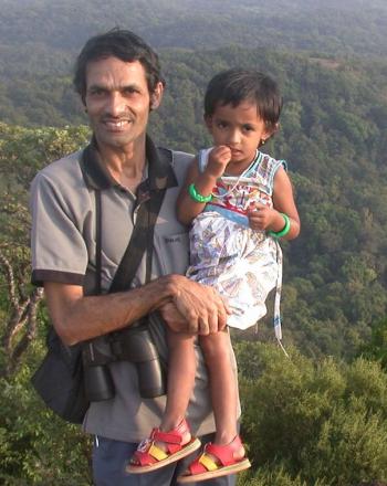 El hombre sonriente sostiene a su hija sobre un fondo exuberante.