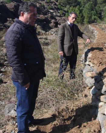 Two men at dam made of stone.