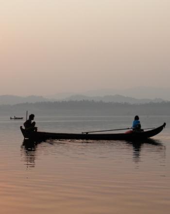 Canoe with two people at sunrise or sunset.