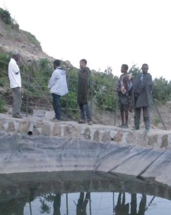 Quelques hommes debout près d'un bassin d'eau artificiel.