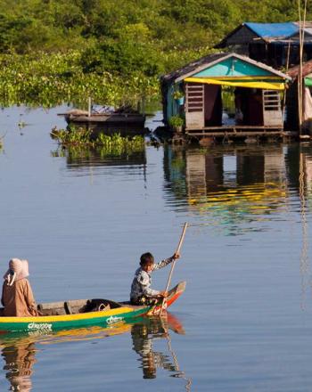 Canoa de colores brillantes en el lago con dos personas, se dirigió hacia varios edificios flotantes.