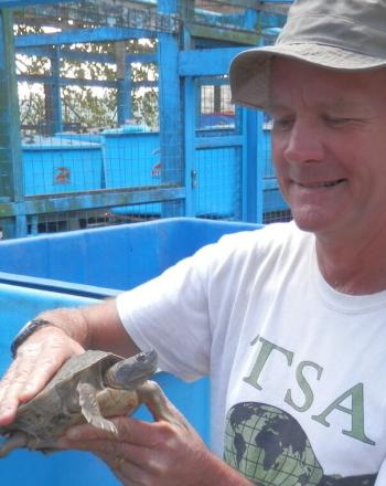 Man with TSA shirt holding small turtle.